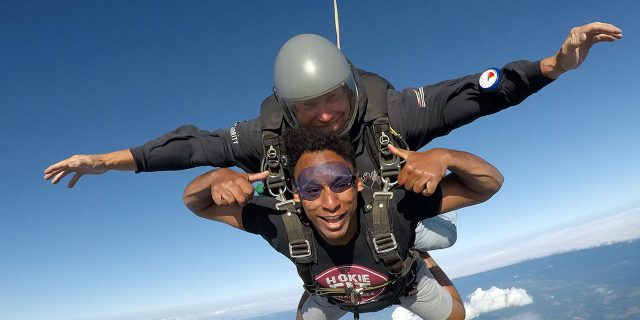 young man gives thumbs up in skydiving freefall